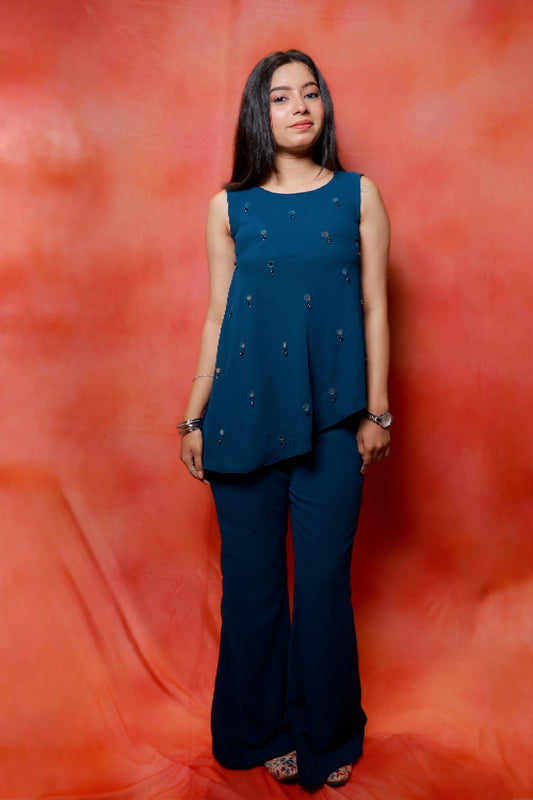 Model wearing the Nysa Teal Mirrorwork Co-ord Set in premium georgette featuring a sleeveless asymmetrical top with mirror work and matching flared pants.