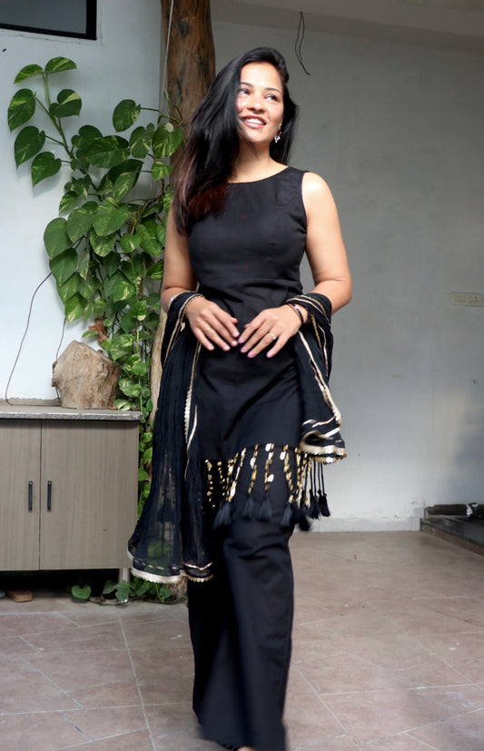 Woman wearing the Tisya Black Suit Set featuring an elegant black kurta, matching bottoms, and coordinated dupatta by Anaykaa.